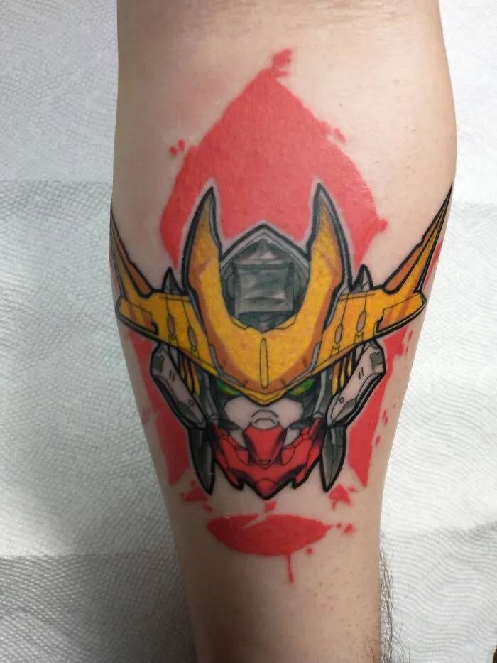 Colorful tattoo of a stylized robot helmet with red paint splashes in the background.