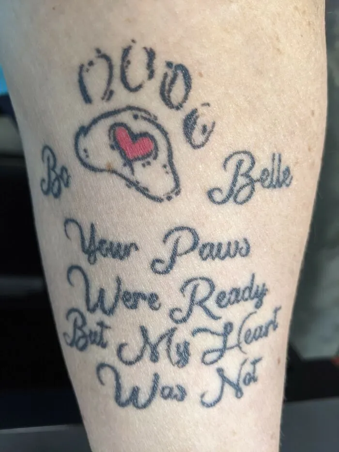 Tattoo with dog paw prints and heart, featuring text "Your paws were ready but my heart was not."