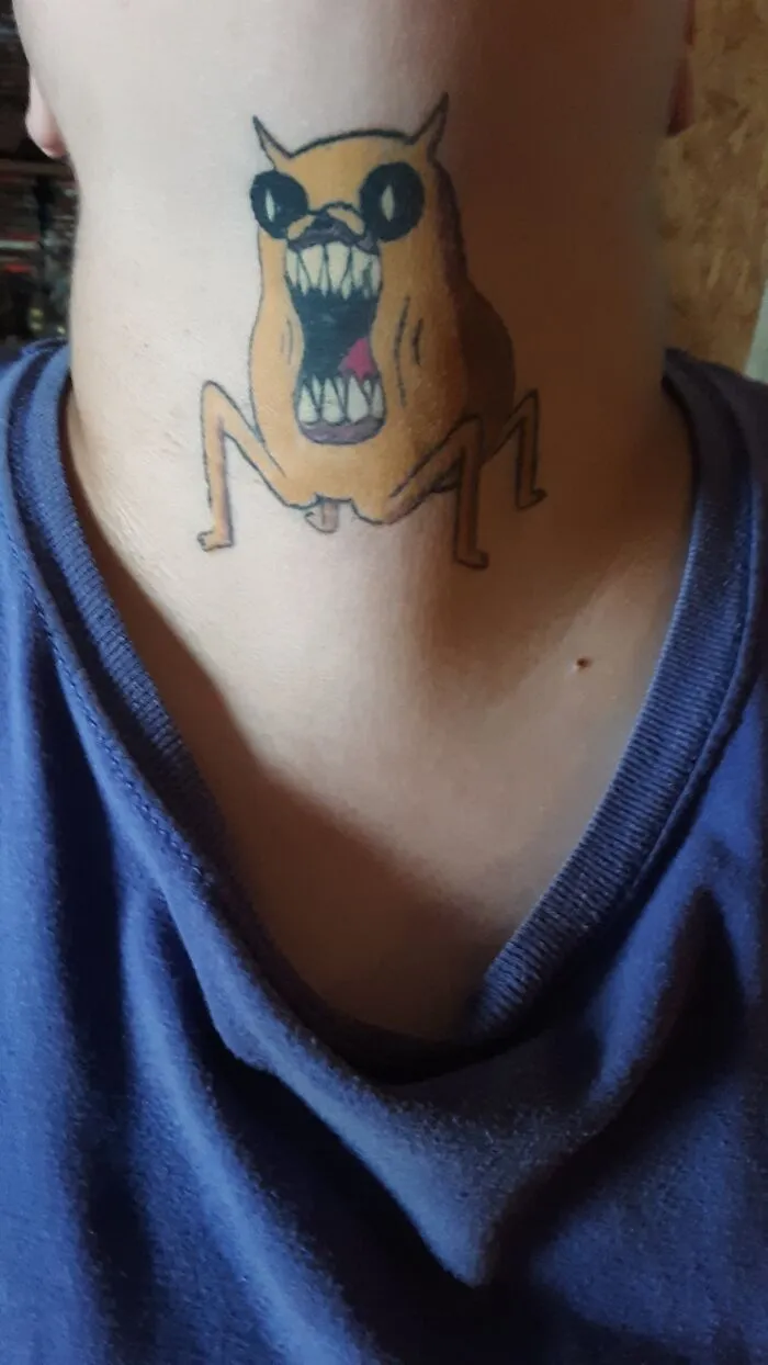 Tattoo of a cartoonish creature on the neck, showcasing unique tattoo art.