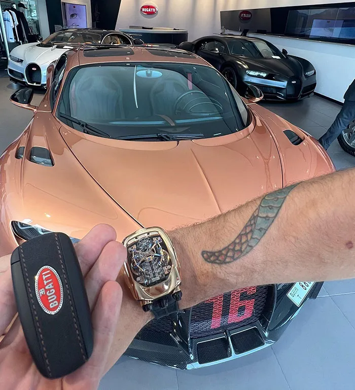 Luxury car showroom with Bugatti, a lavish watch, and key fob flaunting wealth.