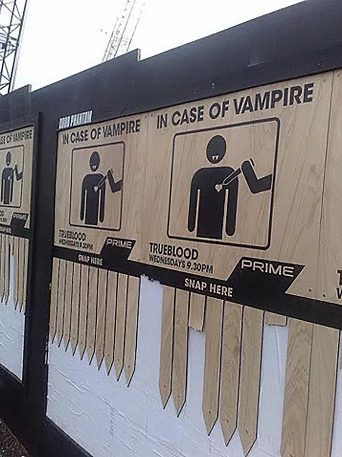 Funny sign showing wooden stakes labeled "In Case of Vampire" with a TV show promotion below.