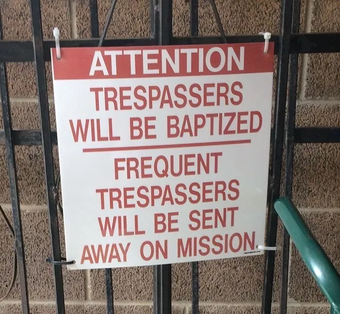 Humorous sign warning trespassers of baptism and frequent trespassers being sent on missions.