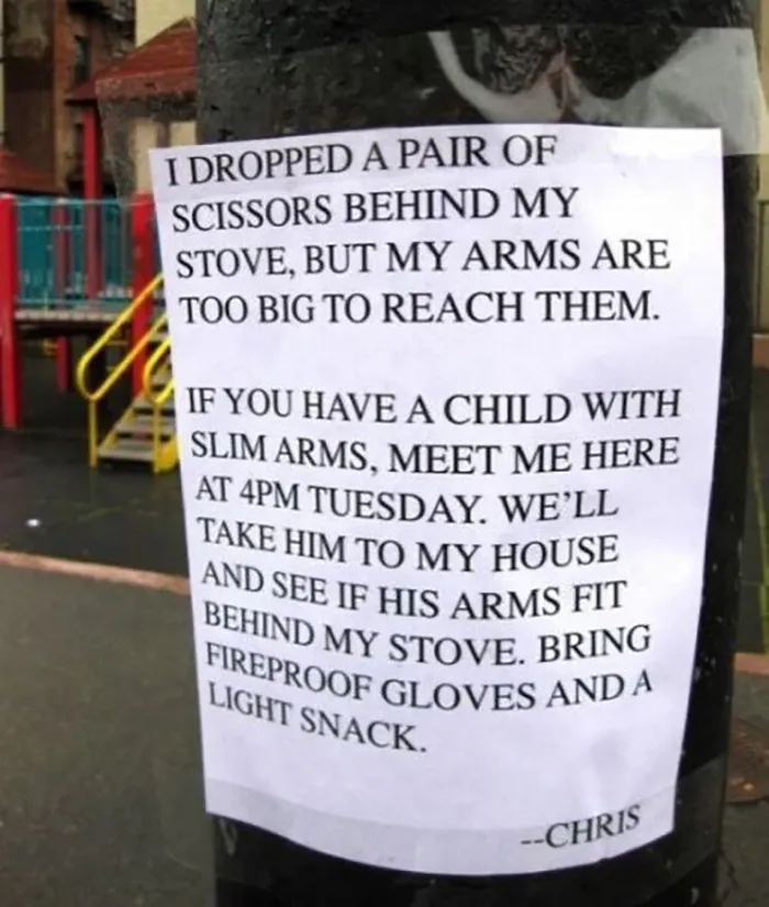 Funny sign on a pole humorously asking for help retrieving scissors behind a stove using a child with slim arms.