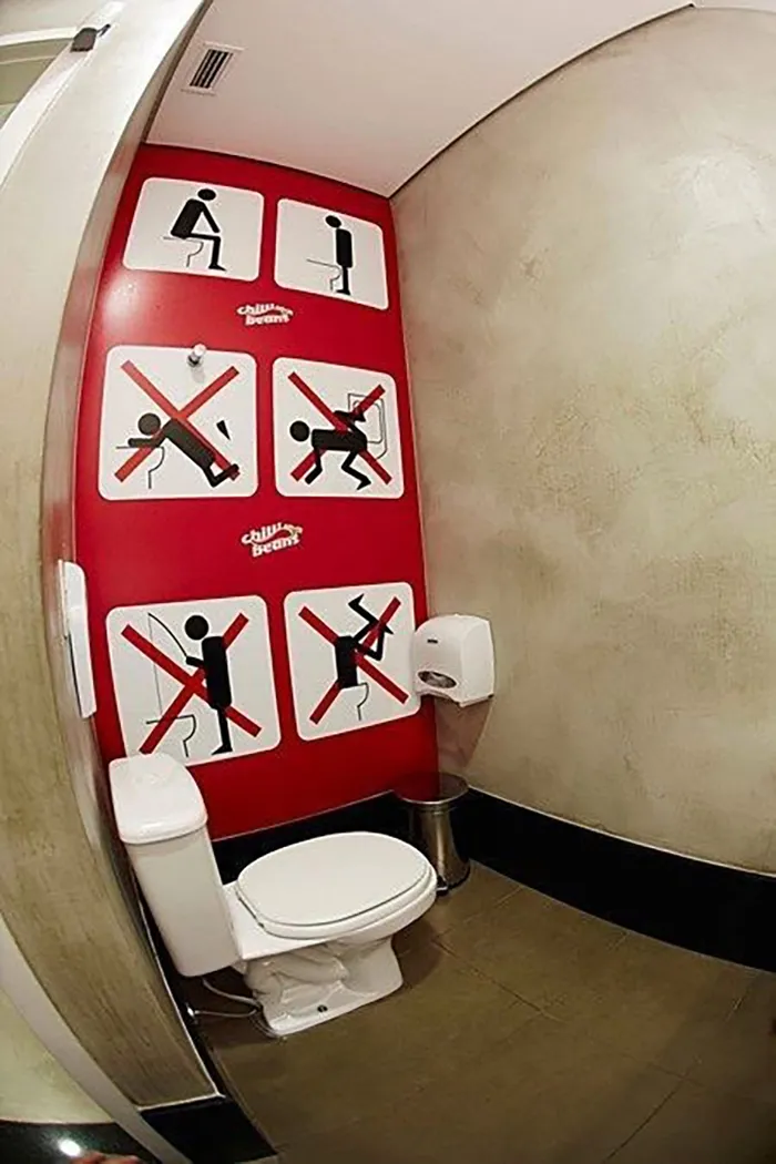 Humorous bathroom sign illustrates incorrect toilet positions with comical stick figure drawings.