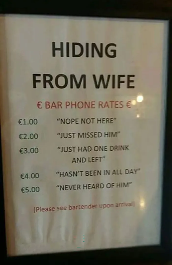 Funny sign in a bar listing phone rates for messages to wives, humorously indicating their availability.