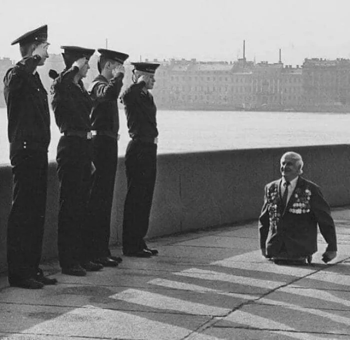 Anatoly Golombievsky, un veterano soviético que perdió las dos piernas durante la batalla de Novorossiysk, durante la Segunda Guerra Mundial, recibe el saludo de 4 cadetes de la Escuela Naval Nakhimov el Día V en Leningrado, 1989