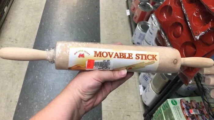 Hand holding rolling pin labeled "Movable Stick" in a store.