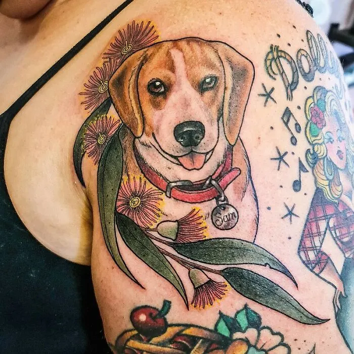 Colorful tattoo of a dog with "Sam" tag, celebrating the bond between humans and pets, adorned with flowers and leaves.