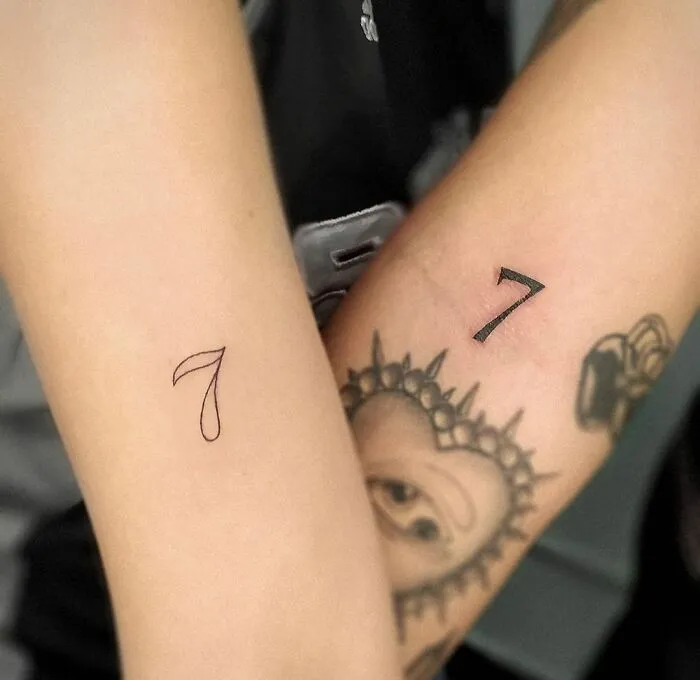 Two arms displaying matching number 7 tattoos for best friends.
