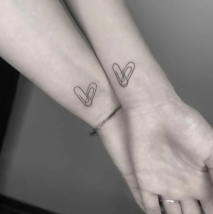 Matching best friend tattoos on wrists featuring intertwined paper clips.