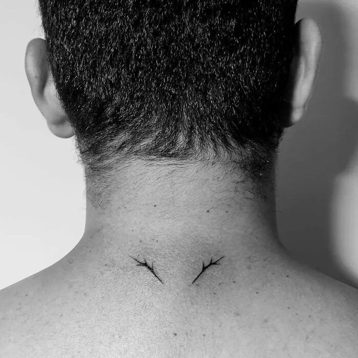 Minimalist tattoo design featuring two fine lines on the nape of a person's neck, showcasing aesthetic simplicity.