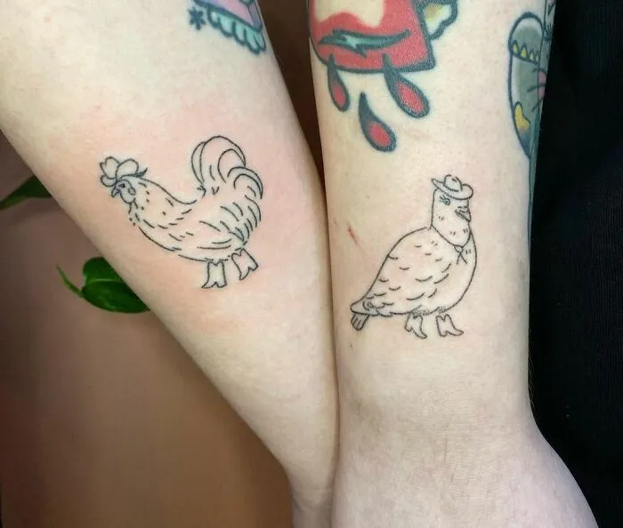 Two arms with matching best friend tattoos of chickens, symbolizing friendship.