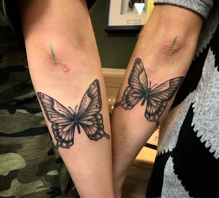 Butterfly best friend tattoos on forearms, symbolizing enduring friendship.