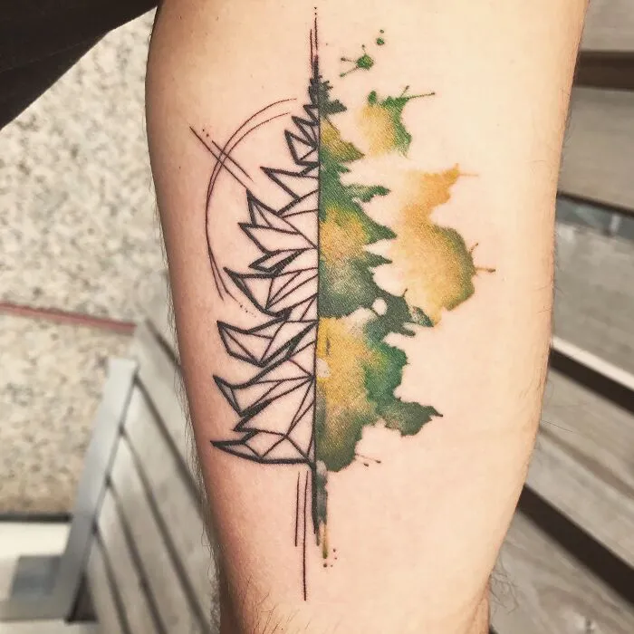 Abstract watercolor tattoo with geometric and organic designs in green and yellow hues on an arm.