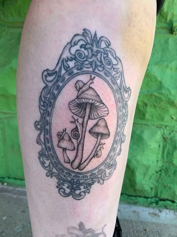 Framed tattoo of mushrooms and a snail, showcasing pet tattoos and celebrating human-pet bonds.