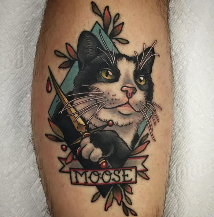Cat pet tattoo with the name “Moose” on a person’s leg, showcasing a bond between humans and their pets.