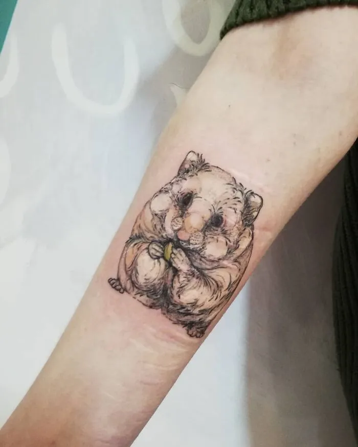 Tattoo of a detailed hamster on a person's forearm, celebrating the bond between humans and pets.