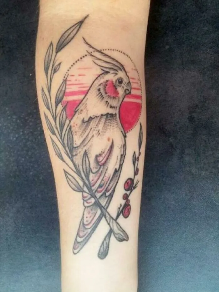 A pet tattoo featuring a cockatiel perched on a branch, celebrating the bond between humans and pets.