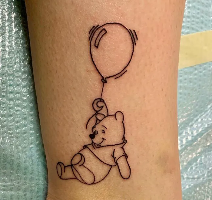 Cartoon tattoo of a bear holding a balloon, inspired by favorite animated shows.