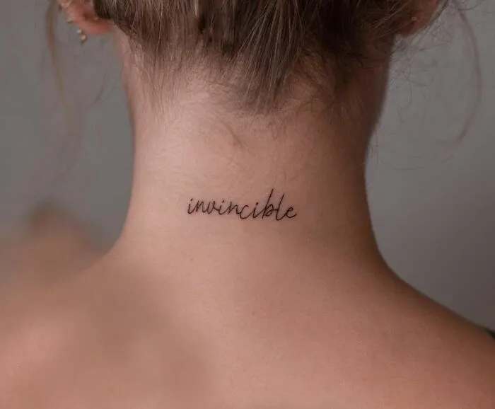Neck with "invincible" word tattoo in cursive, showcasing creative word tattoos for inspiration.