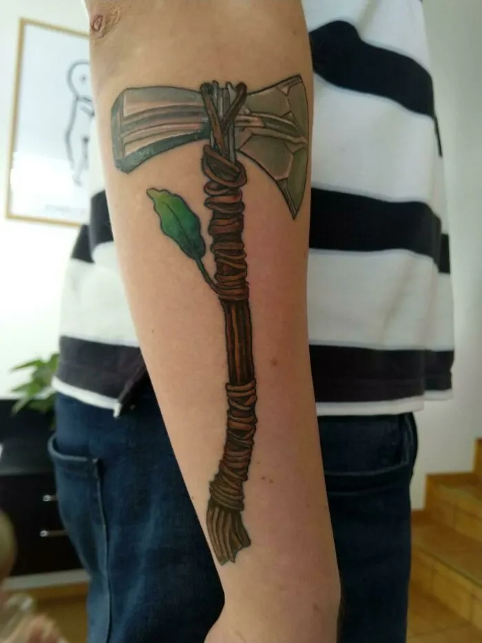 Marvel tattoo featuring Thor's Stormbreaker axe on arm.