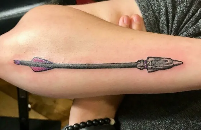 Marvel tattoo of Hawkeye's arrow on a person's arm.
