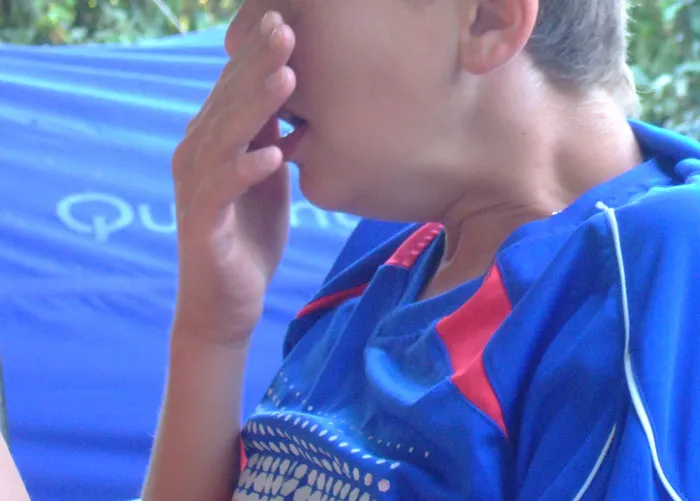 Person in a blue sports jersey outdoors, touching their face; represents bizarre or uplifting personal stories.