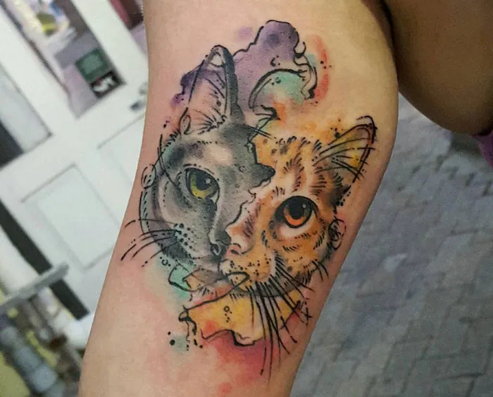 Colorful pet tattoo of a cat's face on an arm, symbolizing the bond between humans and their pets.