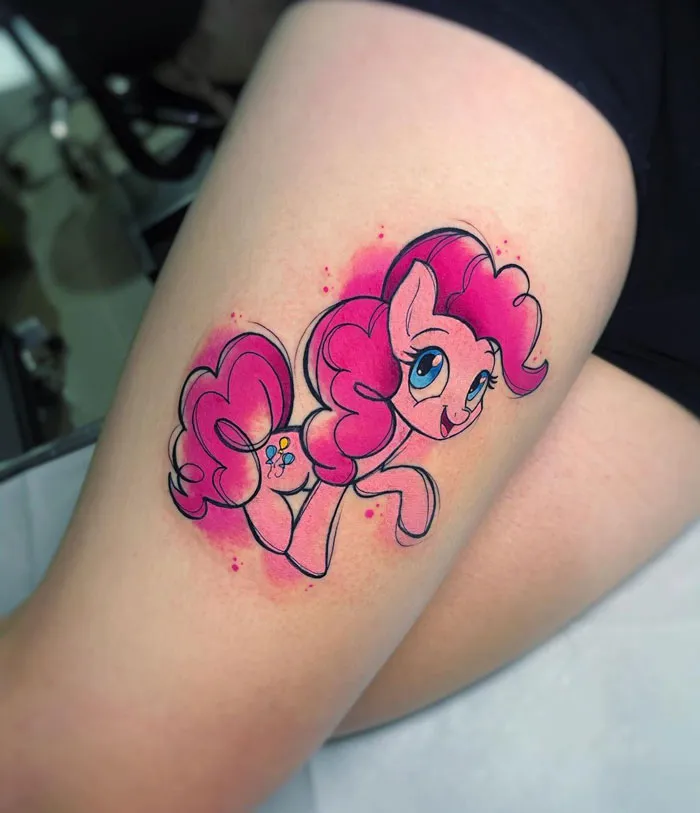 Vibrant pink watercolor tattoo of a cartoon pony on the thigh, showcasing inkspiration.