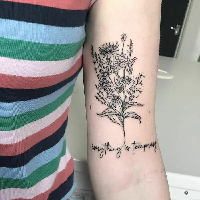 Tattoo of flowers and the phrase "everything is temporary" on an arm, showcasing creative word tattoos.