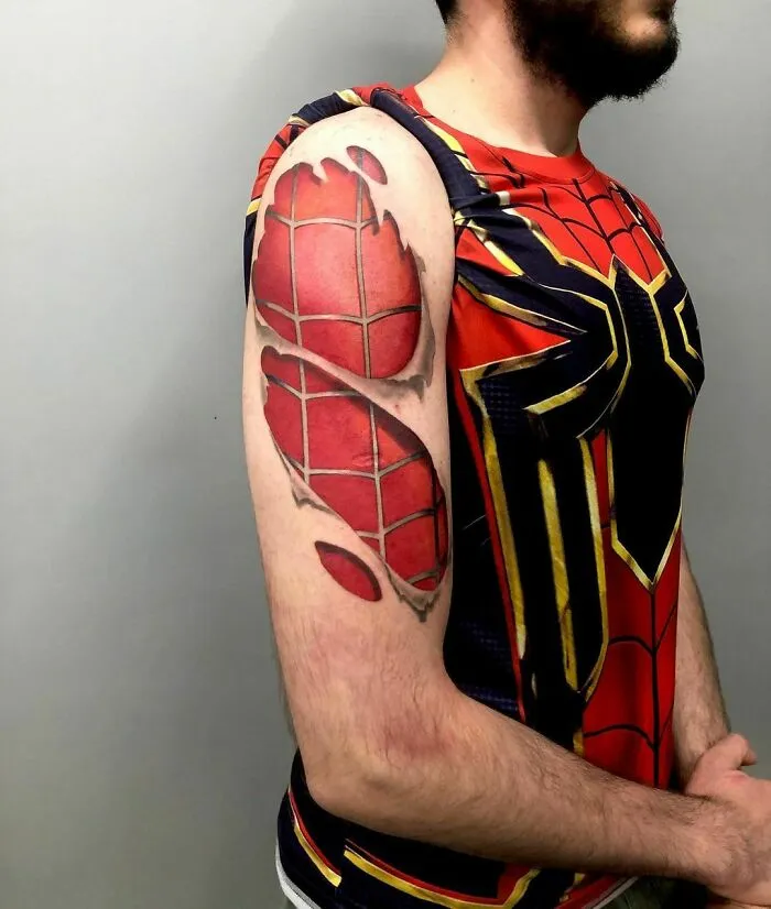 Marvel tattoo of Spider-Man design on a man's arm, wearing a Spider-Man themed shirt, showing intricate detail.