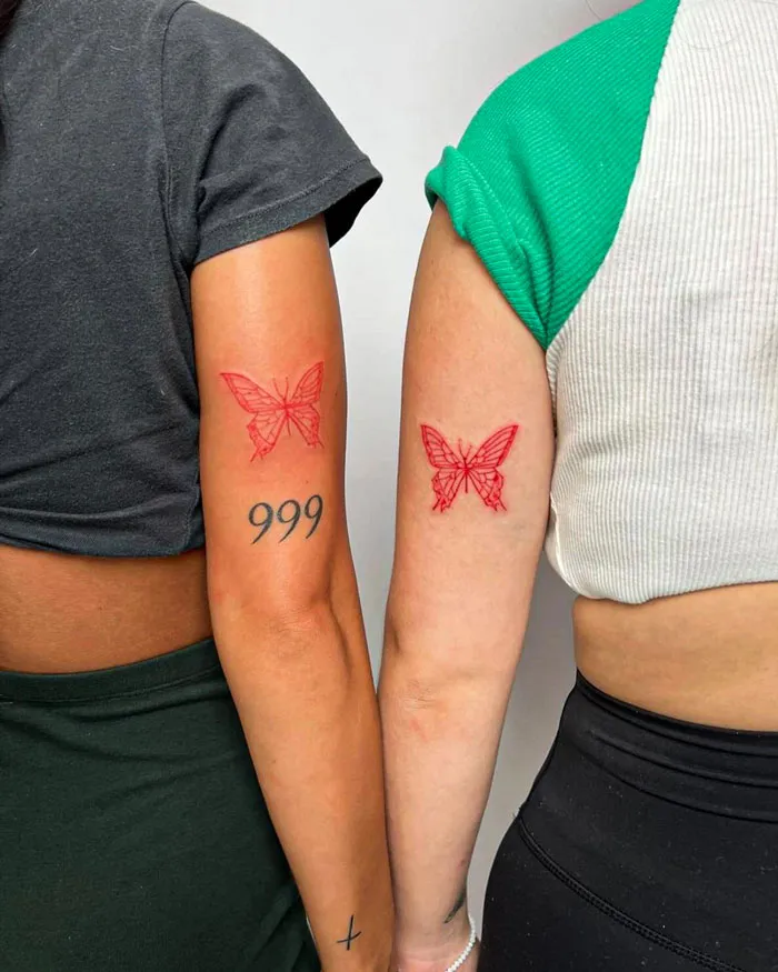Two friends showing matching butterfly tattoos on their arms, symbolizing their friendship.