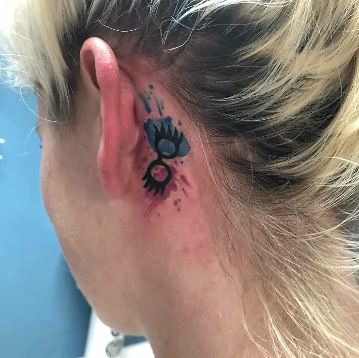 Colorful ear tattoo with a creative abstract design behind ear.