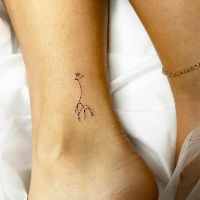 Minimalist tattoo of a giraffe design on an ankle, showcasing aesthetically pleasing tattoo art.