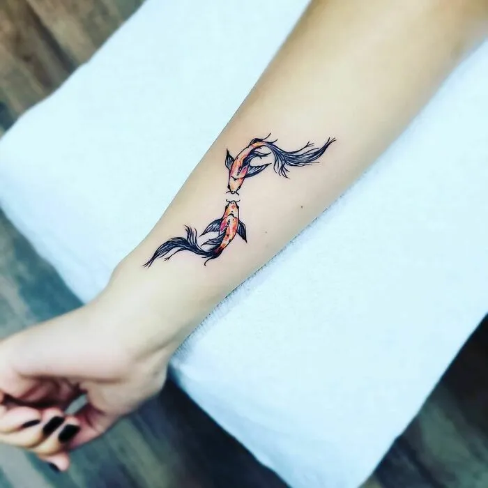 Beautiful watercolor tattoo of two koi fish on an arm, showcasing elegant and intricate ink design.