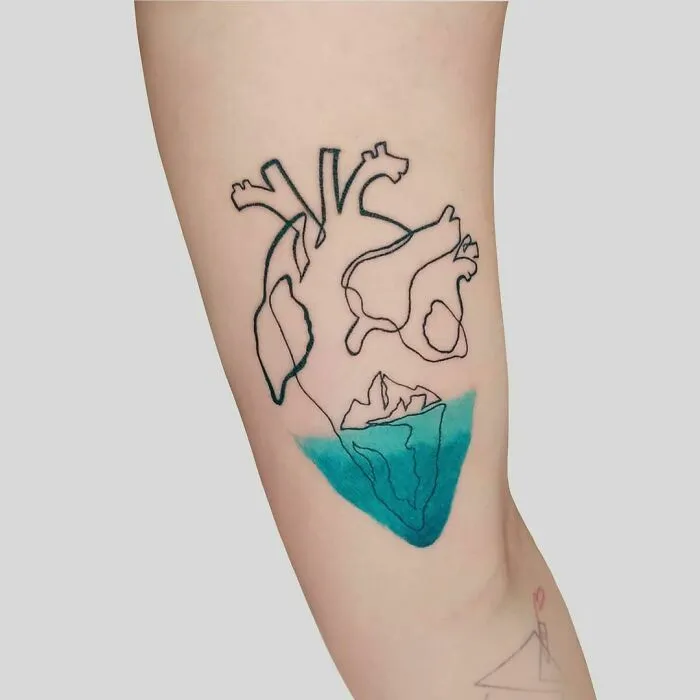 Single-line tattoo of a heart and iceberg with fine-line perfection on arm.