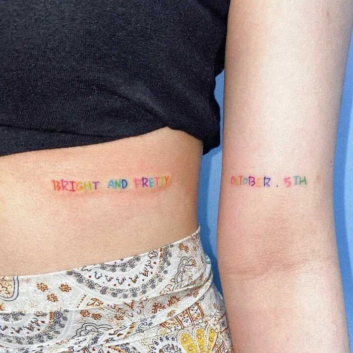 Two colorful word tattoos on a person's side and arm.