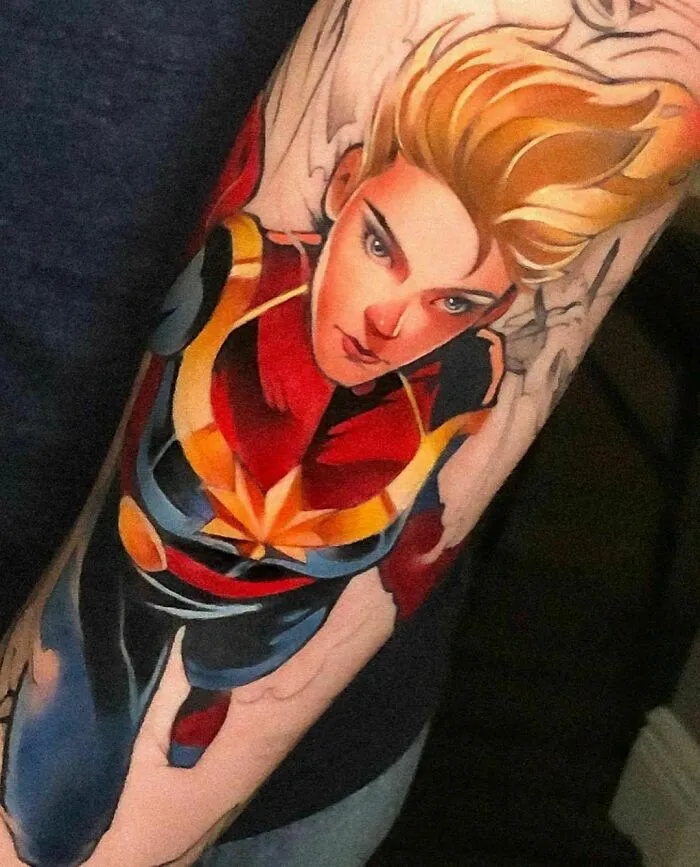 Marvel tattoo of a superhero Captain Marvel in vibrant colors on an arm.