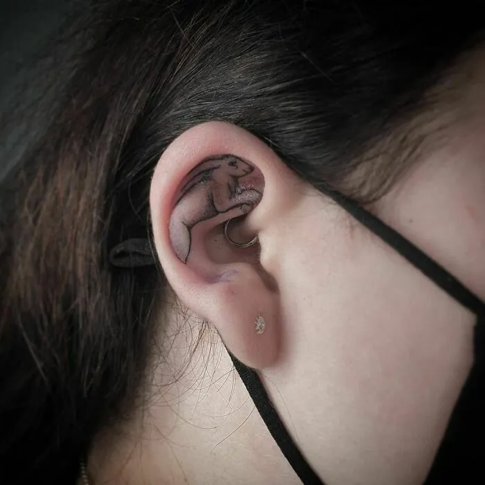 Ear tattoo featuring a rabbit design, placed within the inner ear.