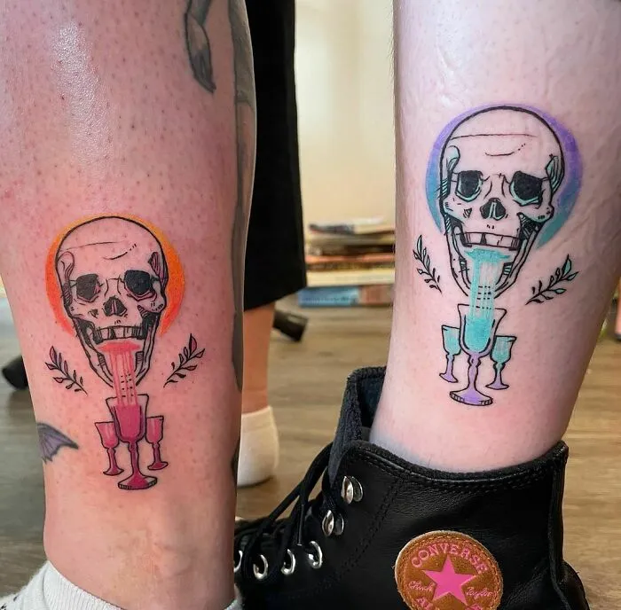 Two best friend tattoos of skulls with colorful drinks on legs, symbolizing friendship.