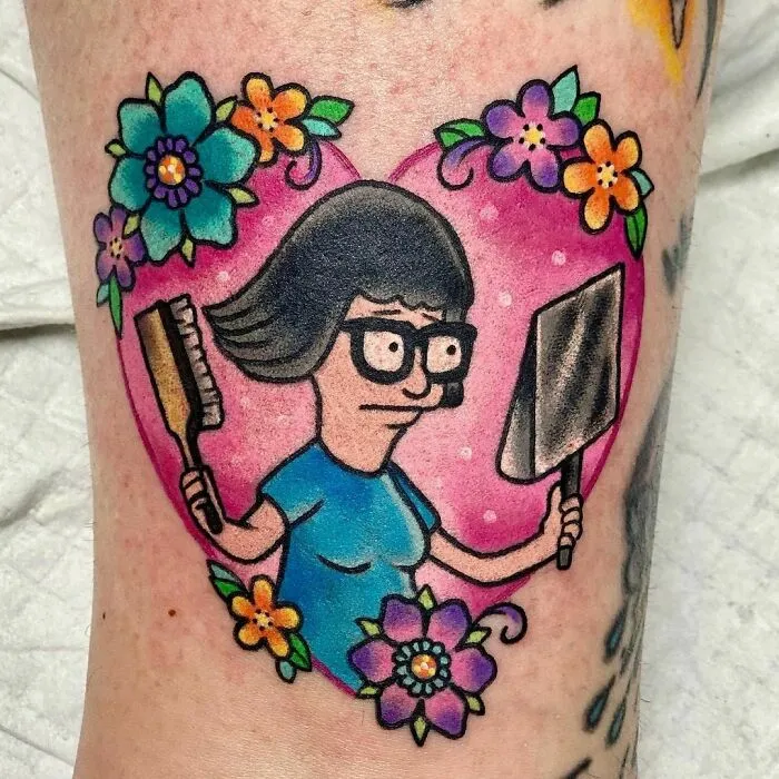Cartoon tattoo of Tina from "Bob's Burgers" with flowers and a heart, embodying a nostalgic theme.