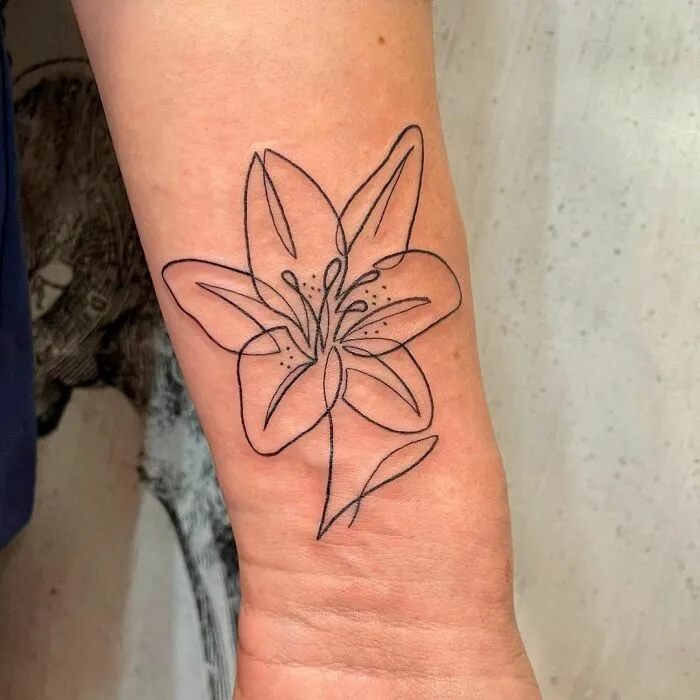 Single-line tattoo of a flower on forearm, showcasing fine-line perfection.
