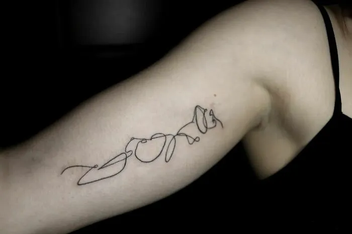 Fine-line single-line tattoo on an arm showcasing intricate design.