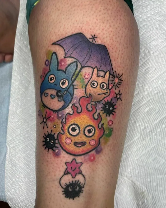 Colorful cartoon tattoo featuring characters from popular animated shows, including creatures with an umbrella and flames.