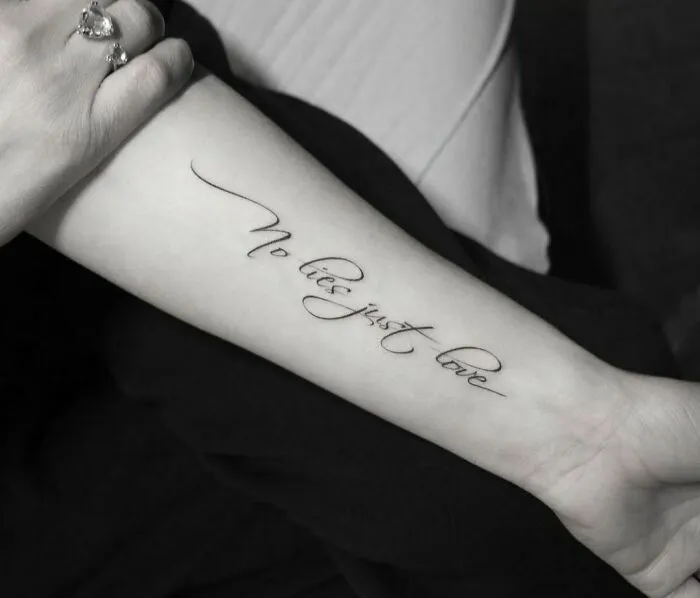 Arm with a word tattoo reading "No lies just love" in elegant script, offering inkspiration for creative tattoo designs.