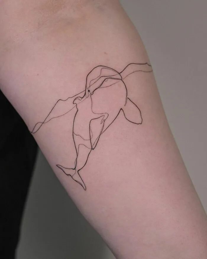 Fine-line tattoo of an orca on an arm, showcasing the elegance of single-line art.