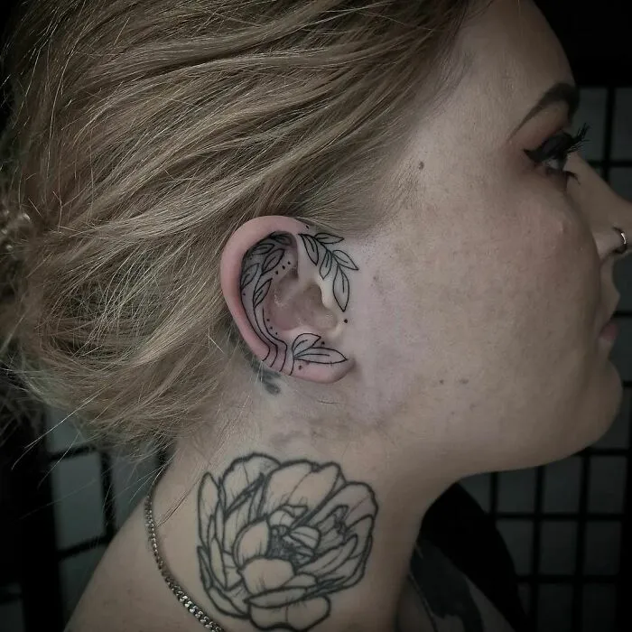 Floral ear tattoo with leaves, showcasing intricate design.