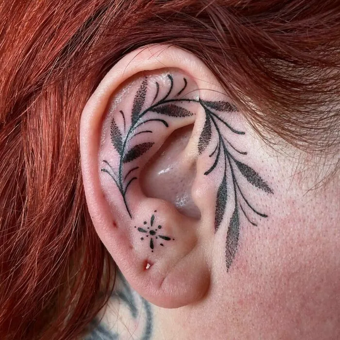 Ear tattoo featuring intricate floral design with delicate black ink detailing.