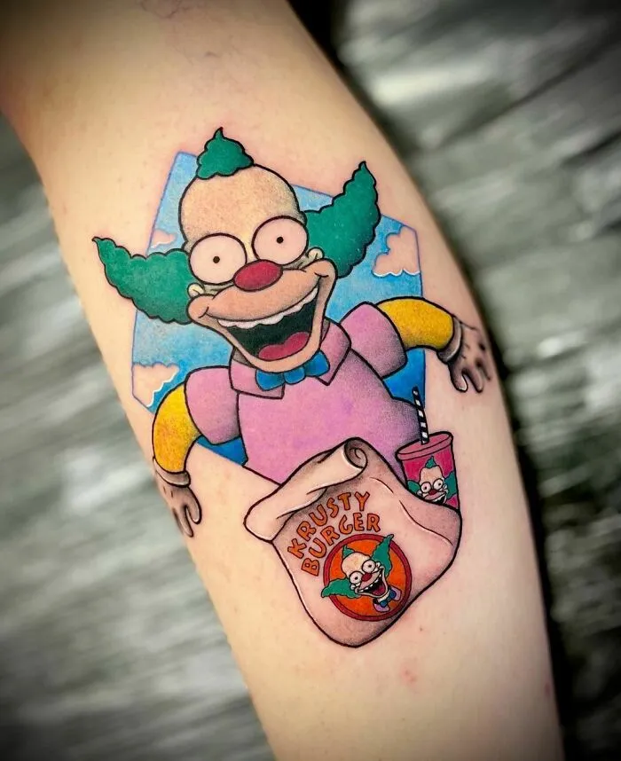 Cartoon tattoo featuring a clown character and Krusty Burger bag in vibrant colors.