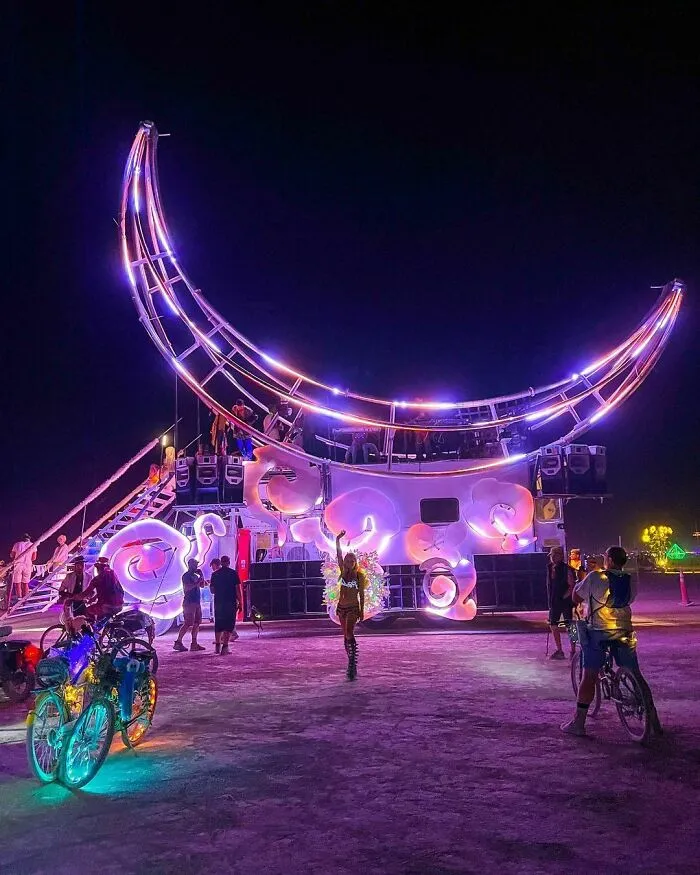 Woman taking photo in front of lighted up moon installation 